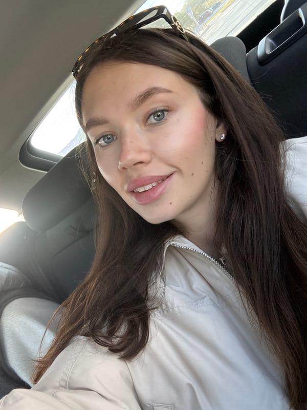 Woman takes smiling selfie in car passenger seat