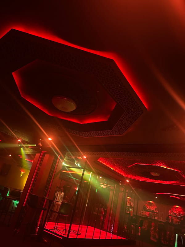 Inside a red-lit Abuja nightclub with historic portrait decor