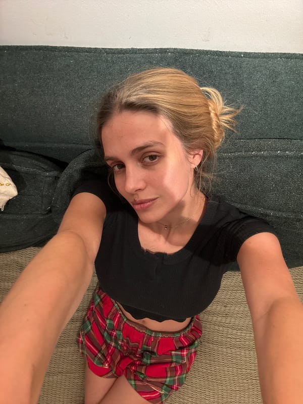 Woman takes selfie on couch in casual attire