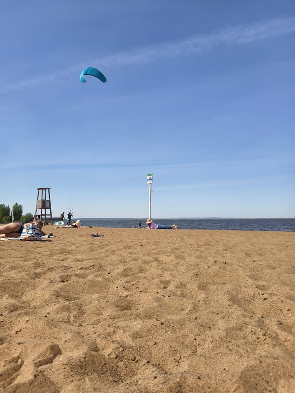 Woman enjoys sunny beach day with kite overhead