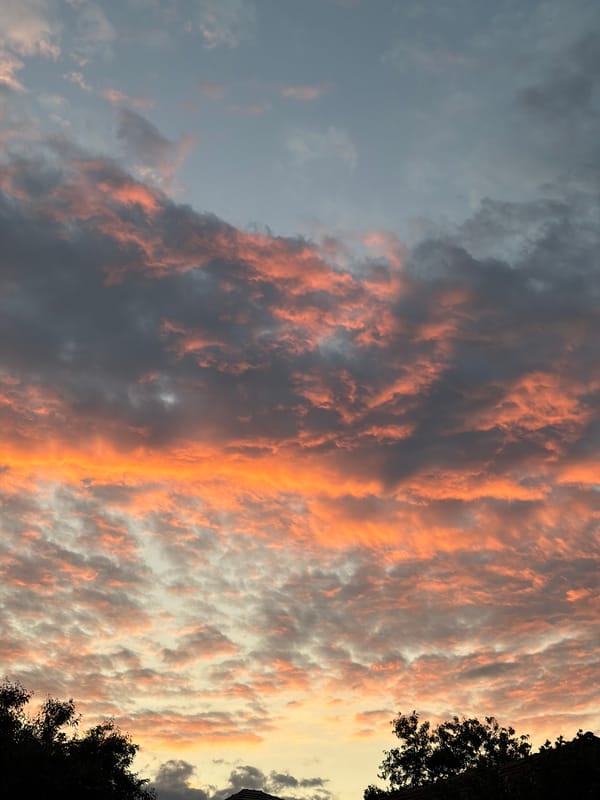 Sunset clouds display orange-pink hues over silhouetted landscape