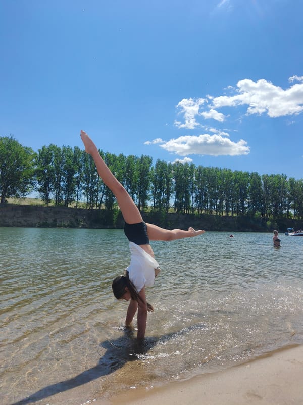 Handstand at the water's edge, legs up in the shallows