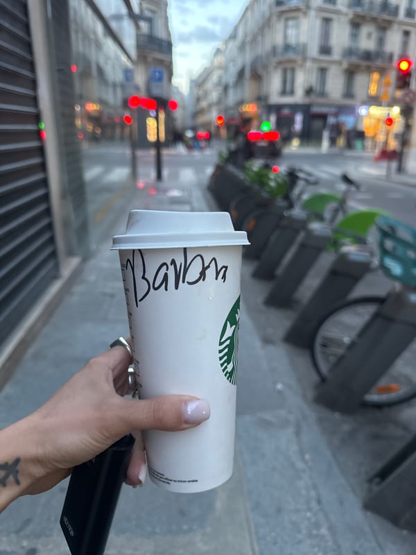 Person holds Starbucks cup and device on Paris street
