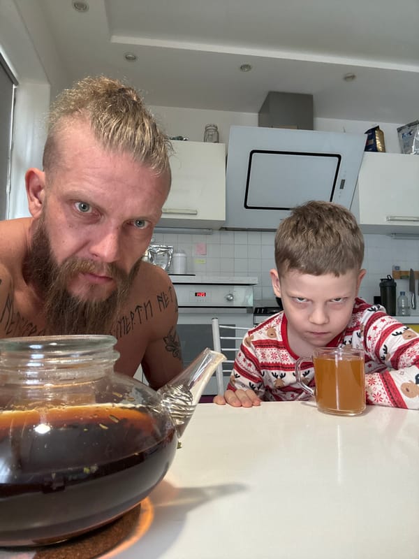 Tattooed man and boy share drinks in Volzhsky kitchen