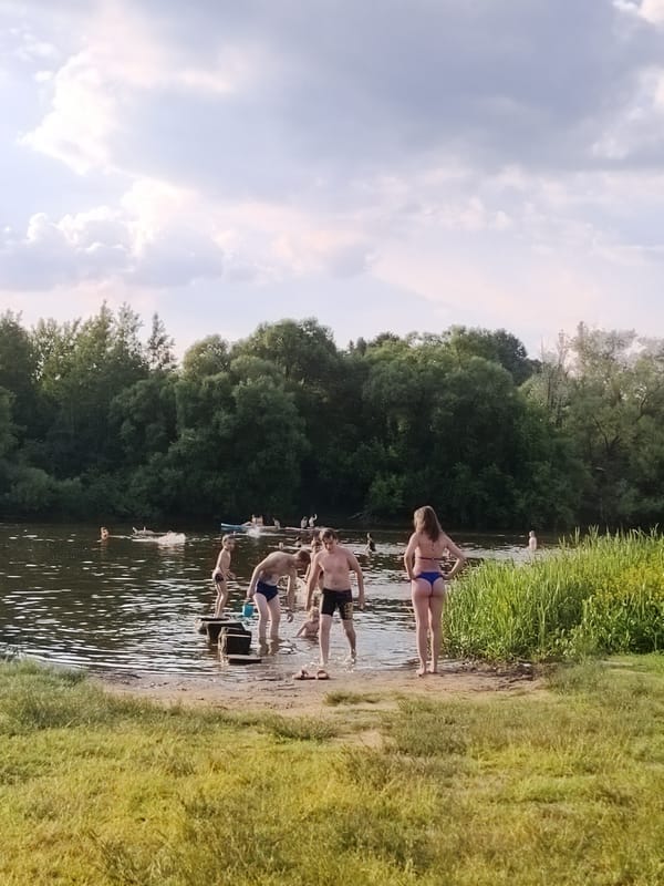 Summer waterfront gathering features swimming, paddleboarding and family recreation