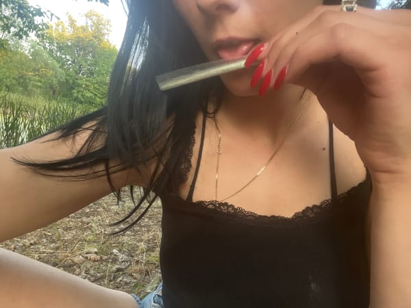 Rolled cigarette and dying campfire, shot in close-up outdoors