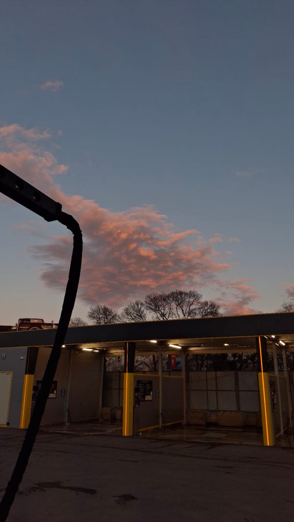 Outdoor carwash photographed at dusk with colorful evening sky