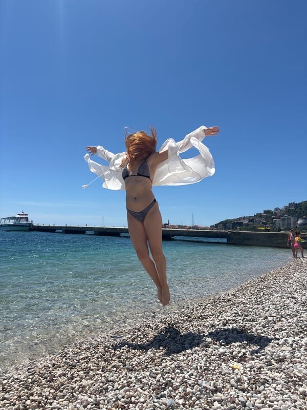 Woman poses and jumps on Budva beach in Montenegro