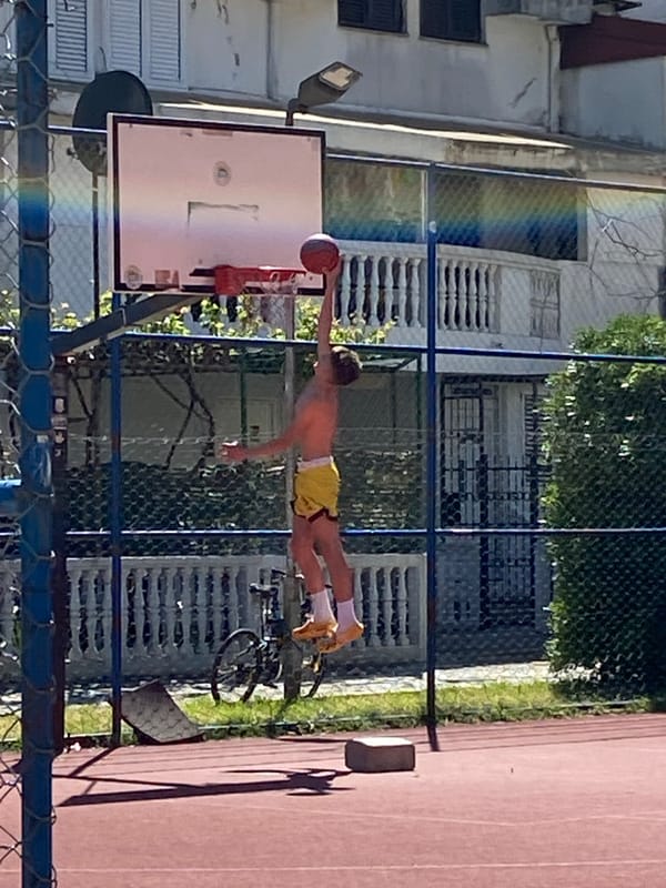 Young player shoots hoops in sunny Budva courtyard