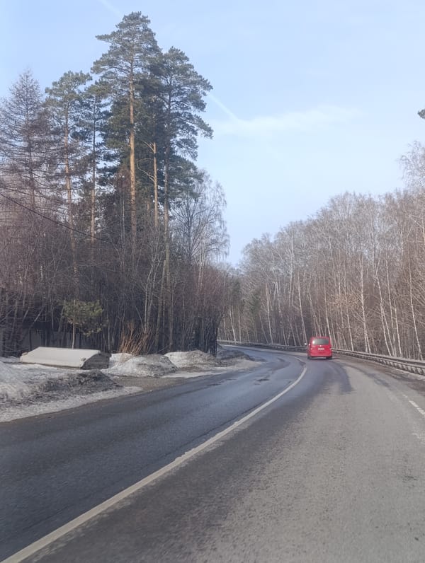 Red vehicle travels wet forest road in Krasnoyarsk