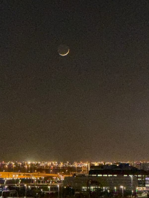 Crescent moon night over a glowing modern city skyline
