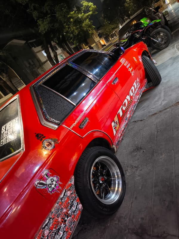 Modified red Toyota with for-sale sign parked at night