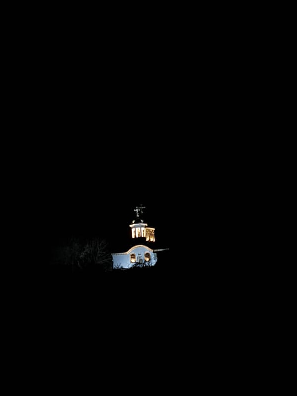 Aerial nighttime view captures illuminated building with cross and trees