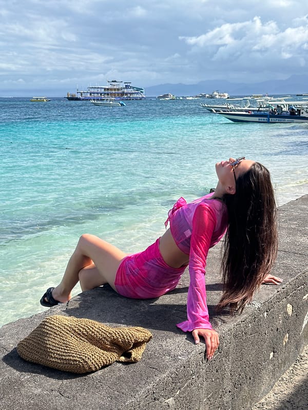 Woman visits Nusa Penida beach pier amid moored boats