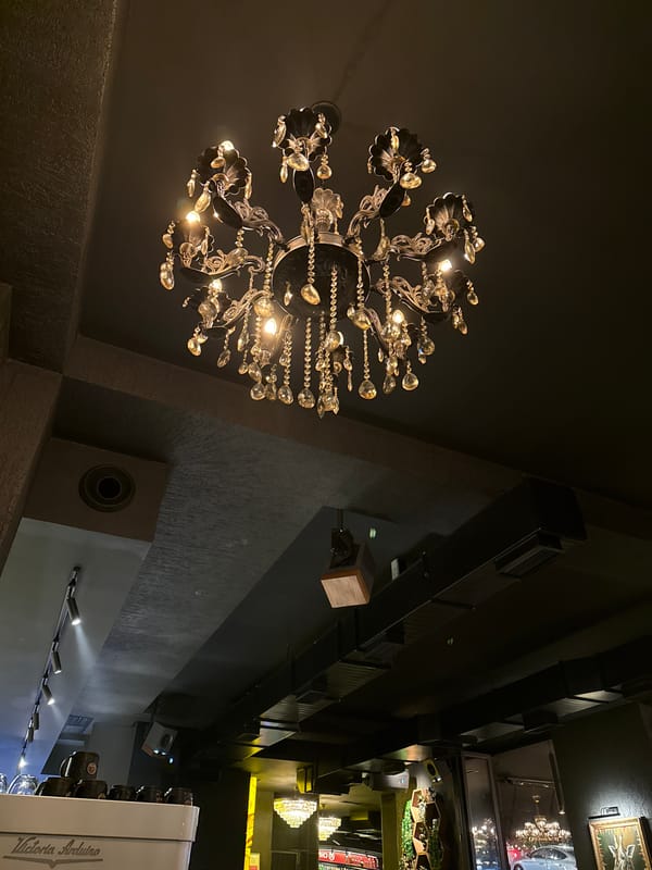 Coffee shop visitor films ornate chandelier during evening visit