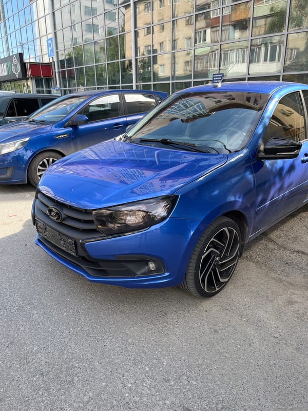 Blue Lada parked outside modern building, inside and out