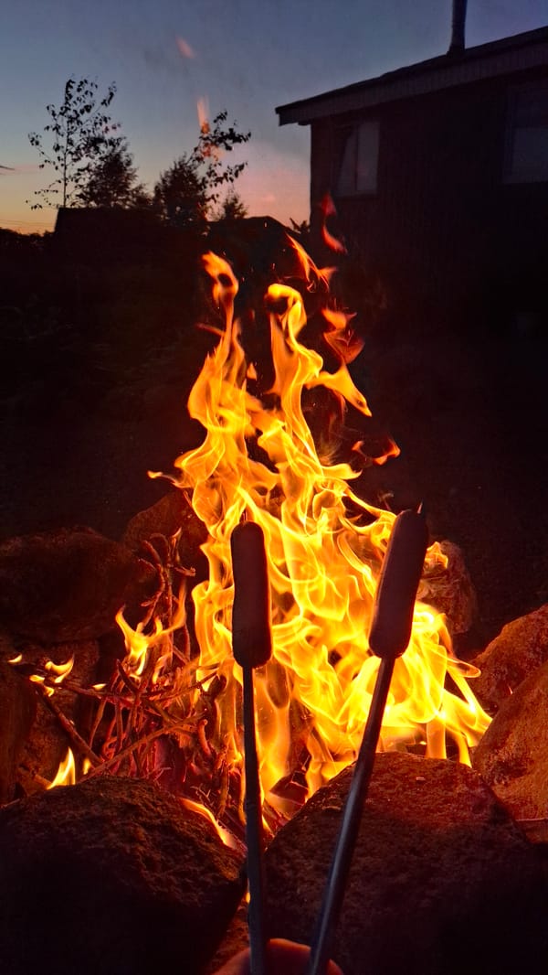 Backyard bonfire and hot dogs over a stone fire pit at dusk