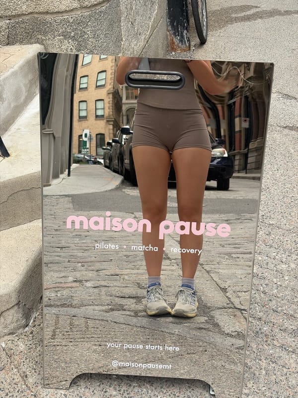 Woman's reflection captured in street mirror sign in Montreal