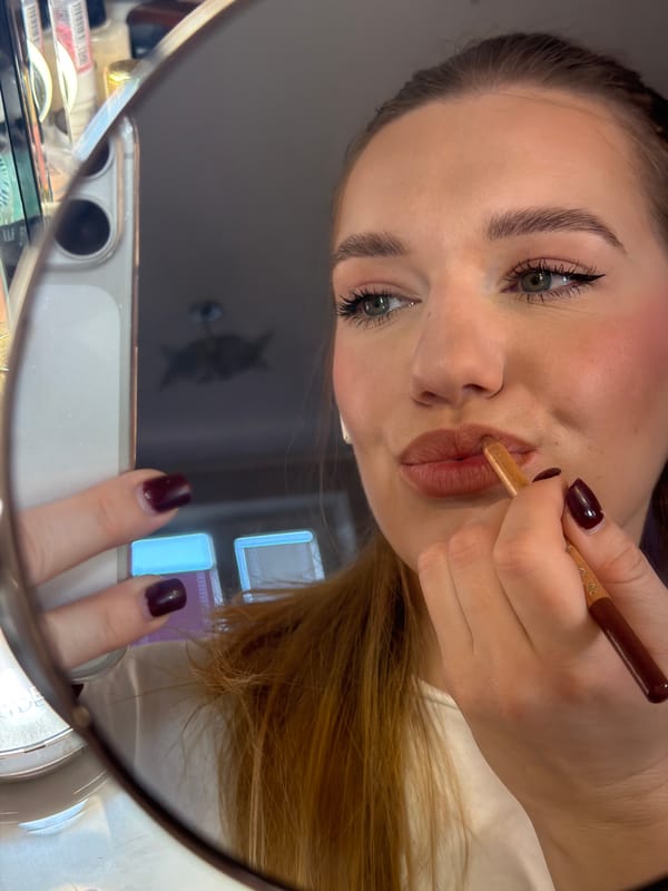 Woman applies makeup in early morning mirror selfie in Latvia