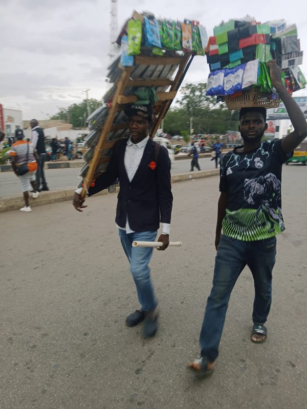 Men walking street in Jos, one carrying goods