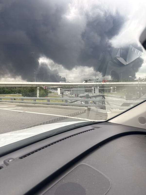 Large dark smoke plume rising over Moscow, seen from a vehicle