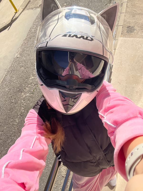 Person in pink seated outdoors in Montenegro coastal town