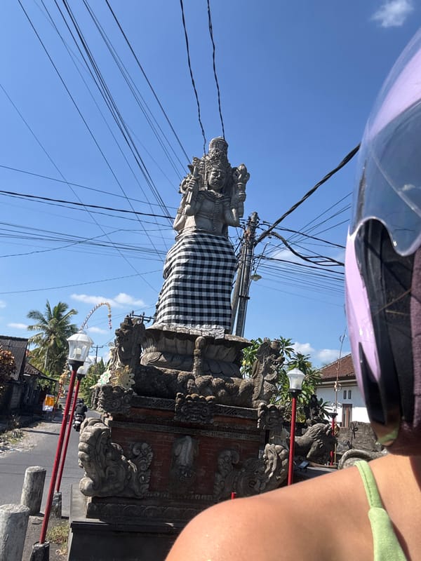 Scooter ride past a ceremonial statue in Kediri, Indonesia