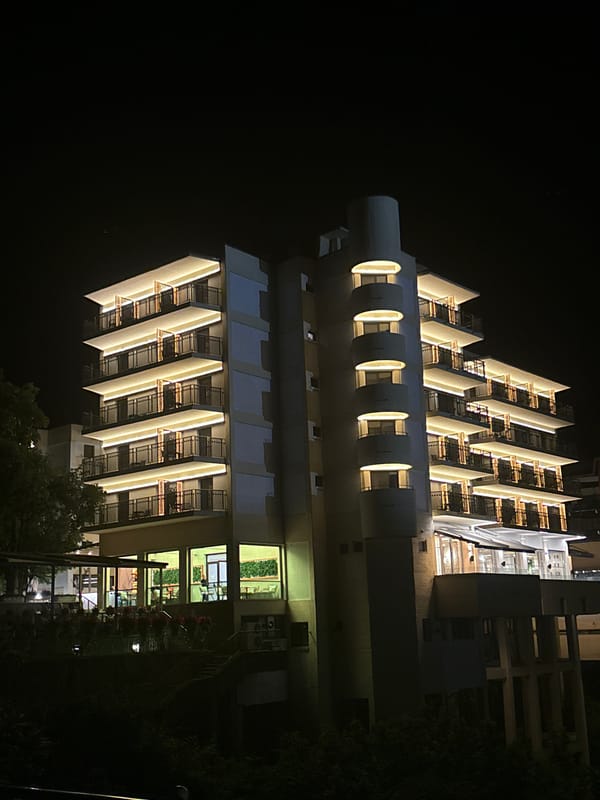 Nighttime urban scene with illuminated buildings and luxury cars