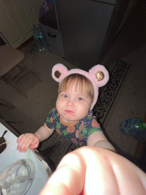 Child and adult wear matching pink bear ears indoors