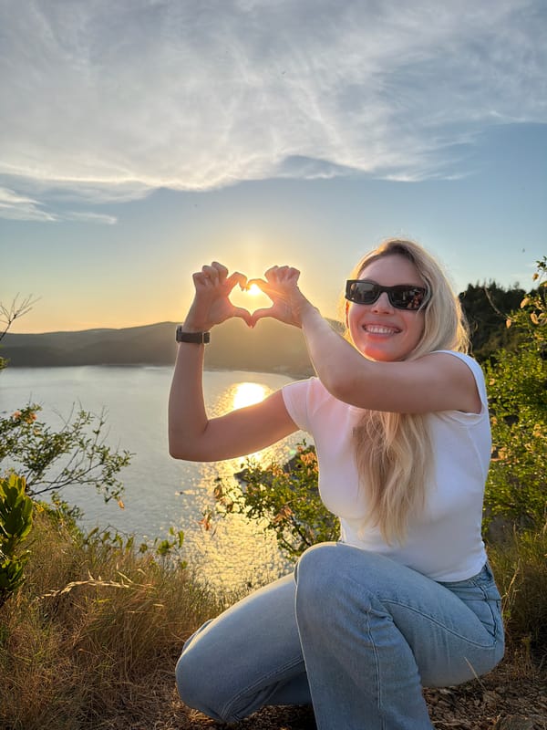 Heart gesture from a rocky Montenegrin bay overlook at sunset