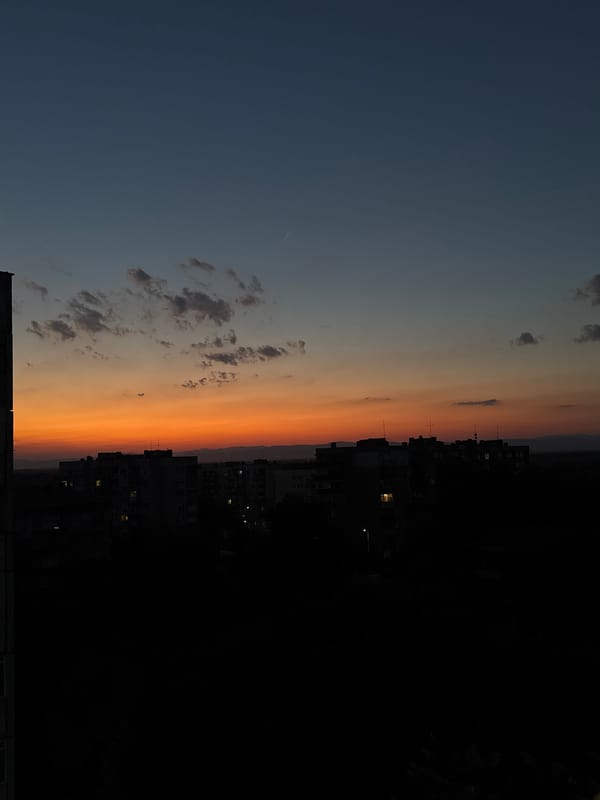 City skyline at golden hour, sky fading blue to orange