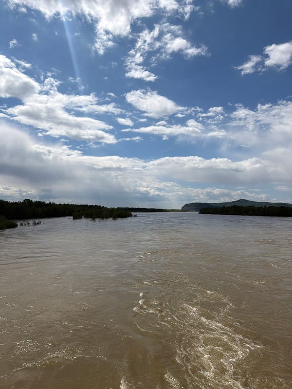 Morning river flows through Kuragino under partly cloudy skies