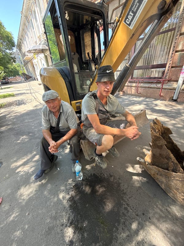 Construction crew works and rests beside a yellow excavator