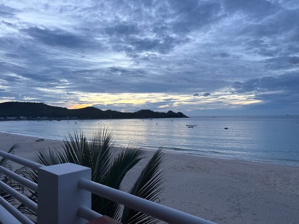 Dusk closes in over a cloudy beachfront shoreline.