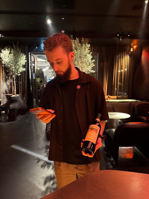 Man holds wine bottle and phone indoors in Dubai