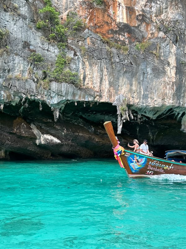 Longtail boat cruising past cliffs and islands at Haad Yao
