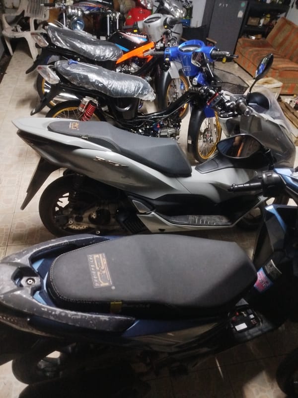 Motorcycles in various states inside a Si Sunthon workshop