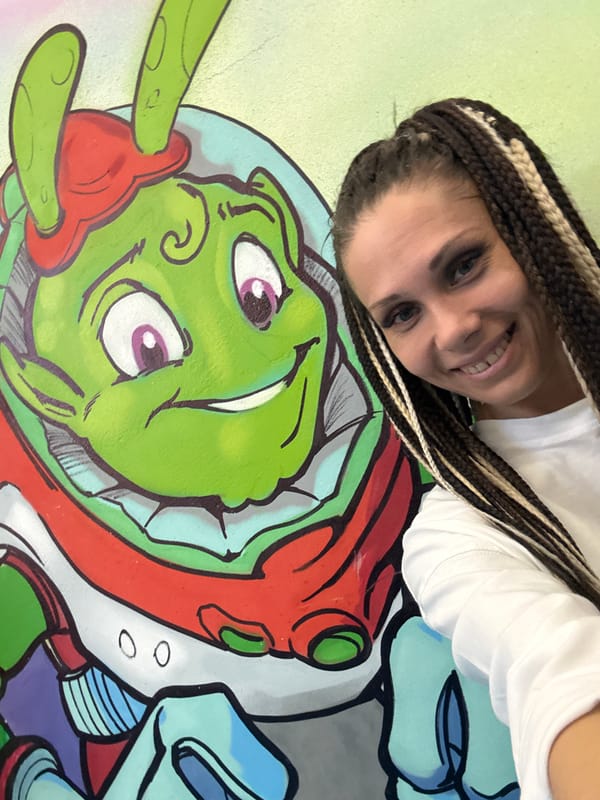 Person poses with alien mural artwork