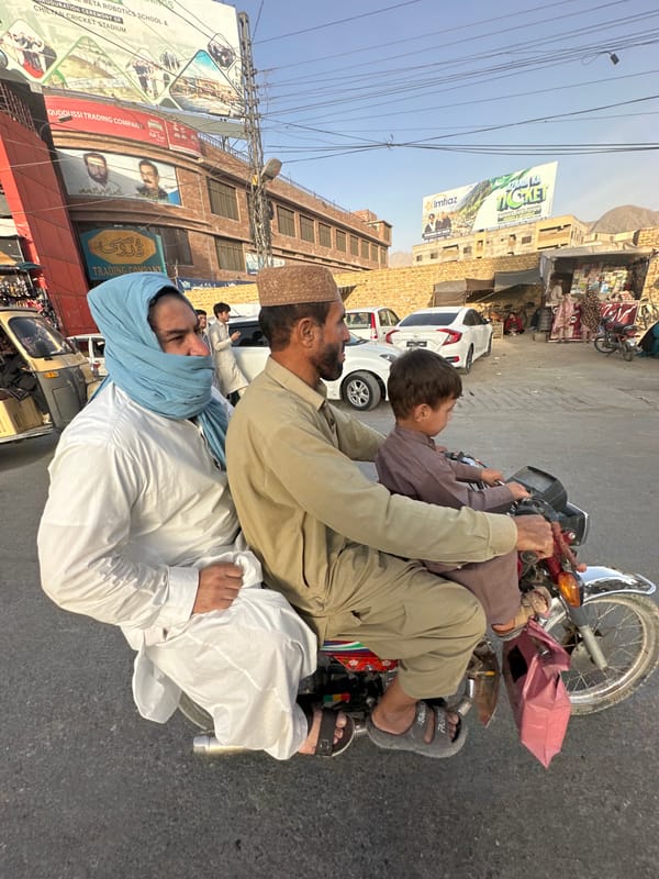 Quetta street market buzzes with traffic, textiles, and daily life.