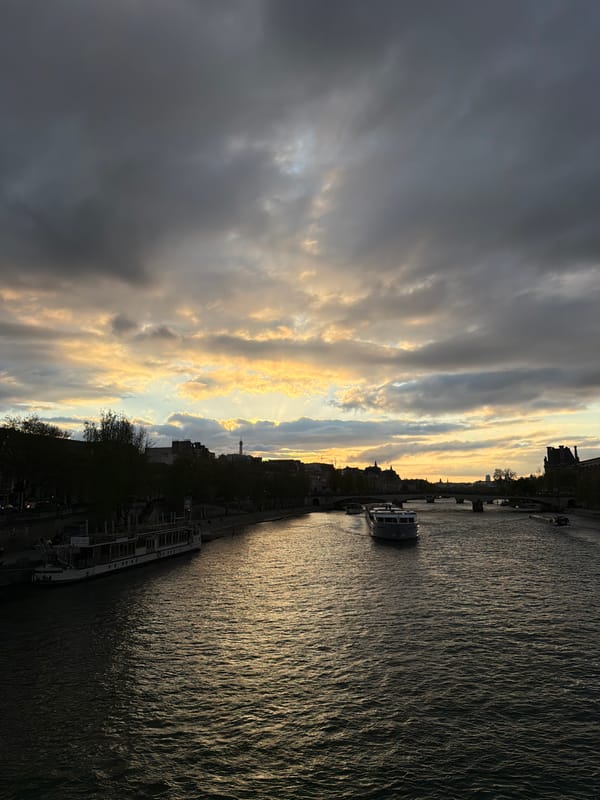 Barge moored along Seine River with pedestrian bridge in Paris