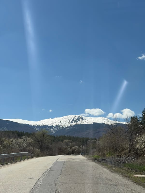 Snow-capped mountains and sunbeams captured near rural Bulgarian road