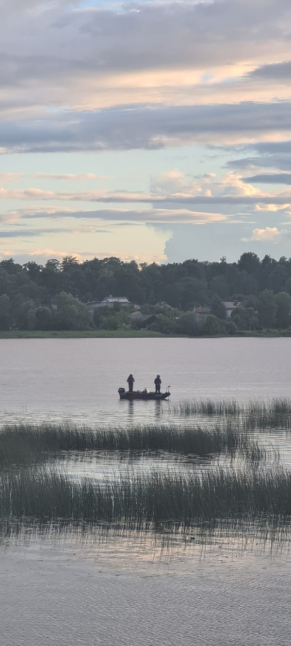 Fishing on open water near a brick-paved area in Riga
