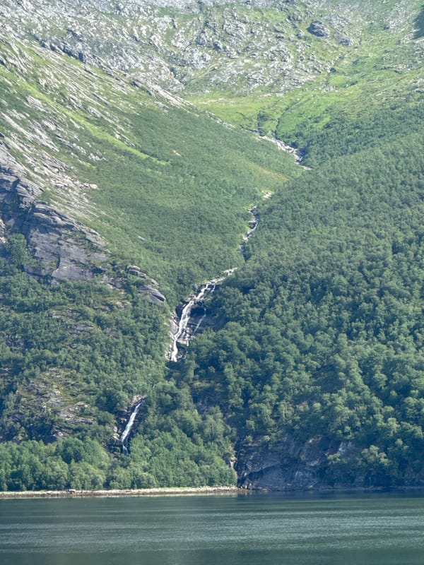 Calm fjord waters and rugged mountain slopes near Inndyr, Norway