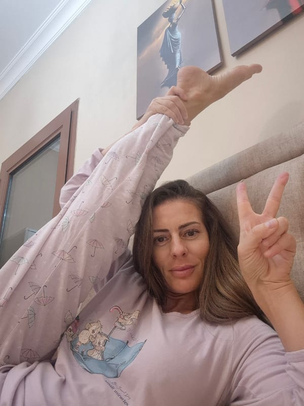 Woman in cartoon pajamas relaxes on couch, makes peace sign