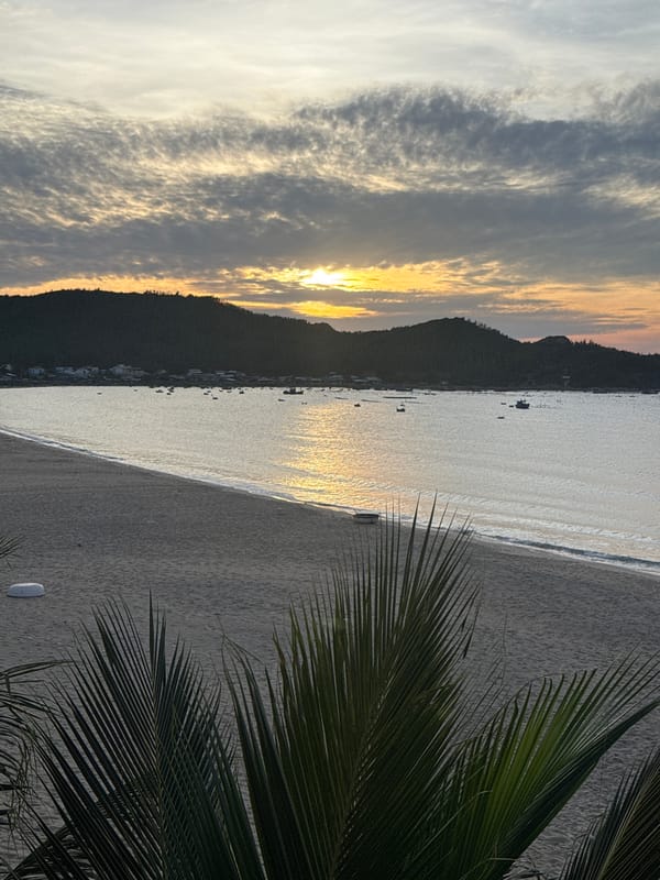 Dusk beach scene with golden sunset over calm water