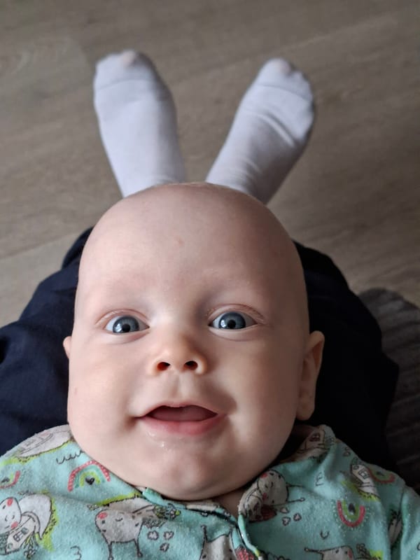 Baby photographed with socks arranged as makeshift rabbit ears