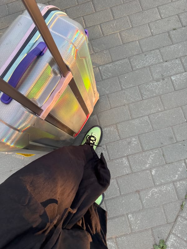 Traveler with iridescent suitcase walks Moscow sidewalk in afternoon sunlight