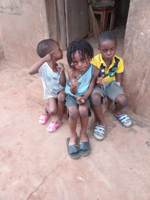 Children rest on ground with scattered shoes in Shagamu