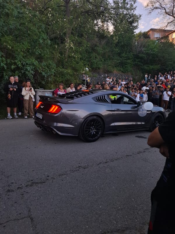 Crowd gathers around cars with flowers in Tsarevo Bulgaria