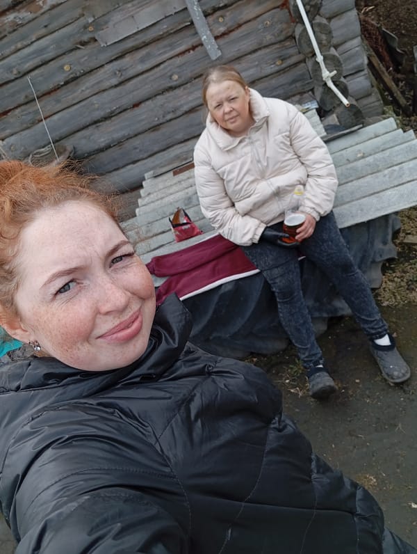 Women socialize outside cabin in rural Russia